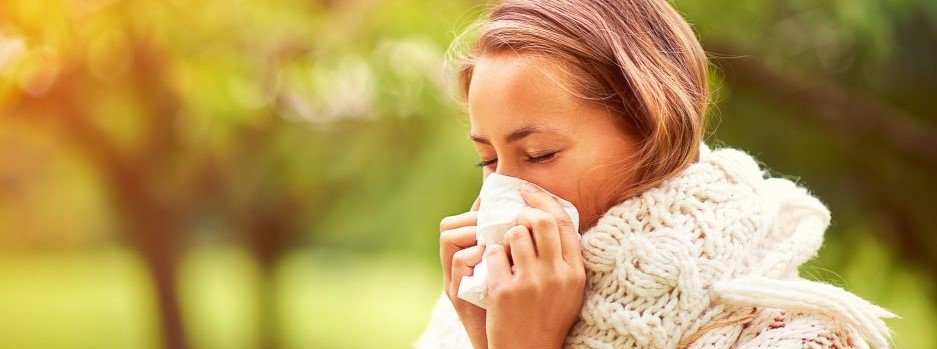 Woman sneezing into a tissue