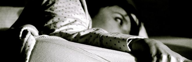 Black and white image of woman lying in bed