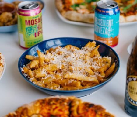 Photo of pub food (pasta, chicken wings, pizza) and drinks (root beer and an IPA beer)