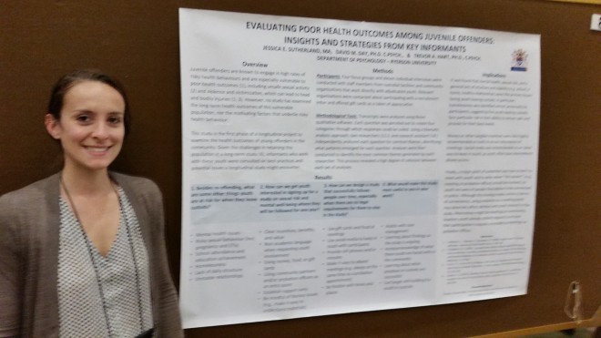 Jessica stands to the left of a presentation poster board.
